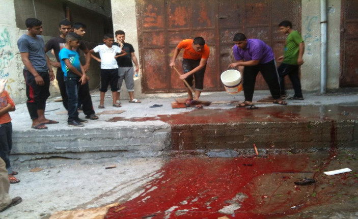 Si lava il sangue lungo il muro perimetrale dell'ospedale di Shifa (Foto: Michele Giorgio)