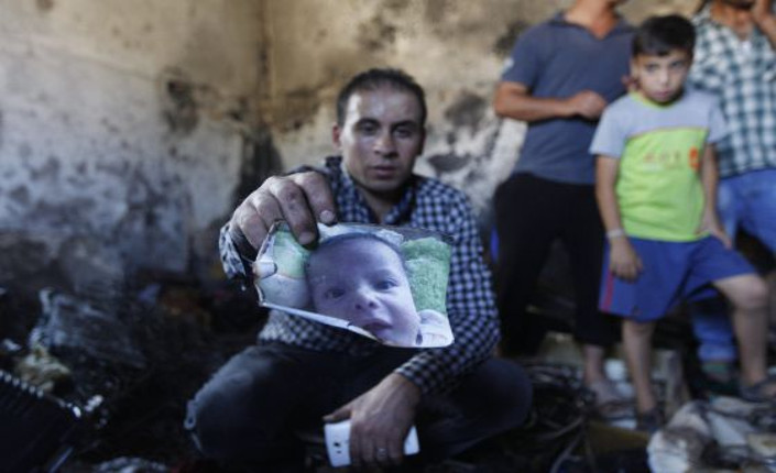 Un parente mostra la foto del piccolo Ali, ucciso nel rogo della sua casa appiccato da coloni israeliani