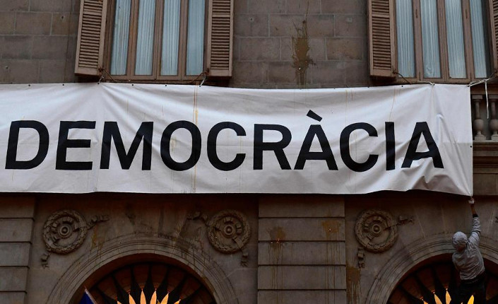 Barcellona. Marcia contro il referendum. Un uomo tenta di togliere lo striscione, con su scritto Più Democrazia, posto sulla facciata del Municipio della città.