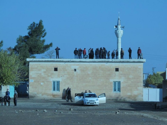 Abitanti di Mehser guardano i combattimenti dal tetto della moschea
